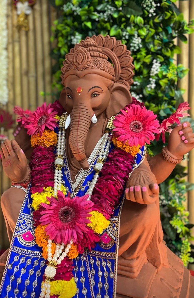 Handcrafted clay Ganpati murti with flower garlands
