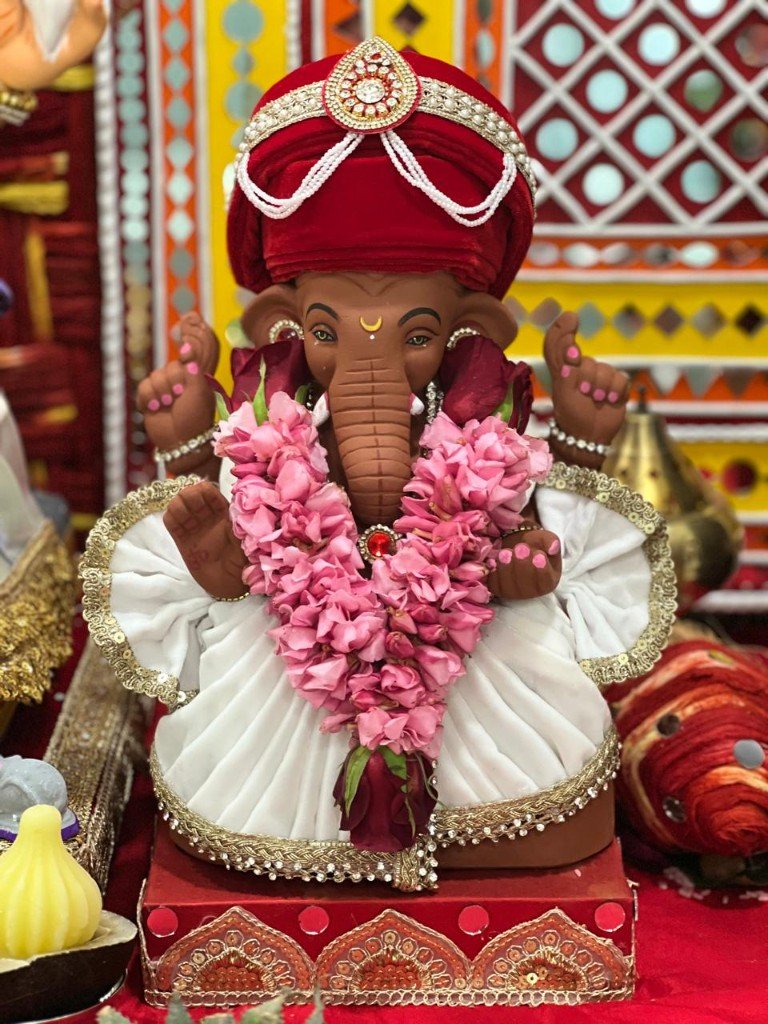 Clay Ganpati murti with pink rose garland